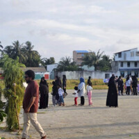 people walking, talking, on a grass field