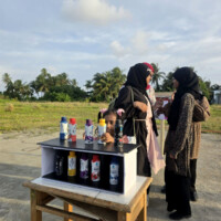 ބޮޓްލް ރޭސް kids playing guess the bottle "rainbow bottle race" game at a carnival