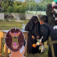 ފީޑް ދަ ލަޔަން young boy throwing a bean bag towards a cardboard lion